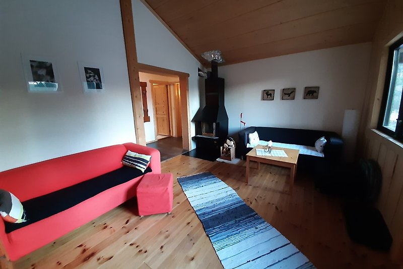 Gemütliches Wohnzimmer mit Holzboden, bequemer Couch und großem Fenster.