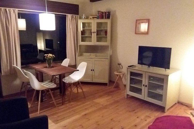 Gemütliches Wohnzimmer mit Holzmöbeln, Bücherregal und Fernseher.