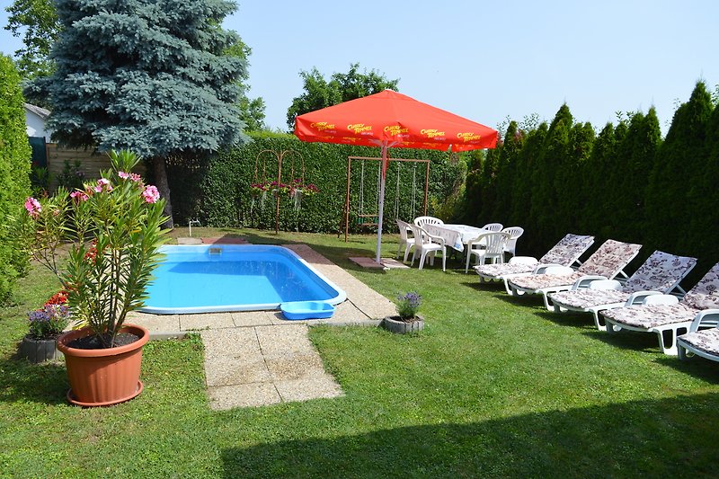 Schwimmbecken mit Sonnenschirm, Möbeln und Pflanzen.