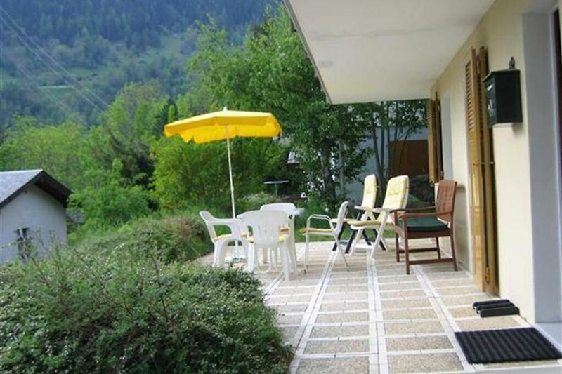 Schöne Terrasse mit bequemen Möbeln und schattigem Sonnenschirm.