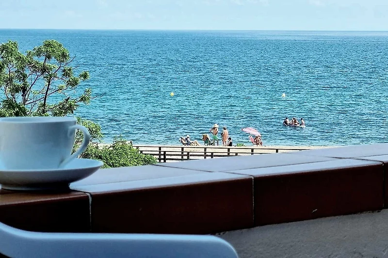 Blauer Outdoorbereich mit Tisch, Stühlen und direktem Meerblick.
