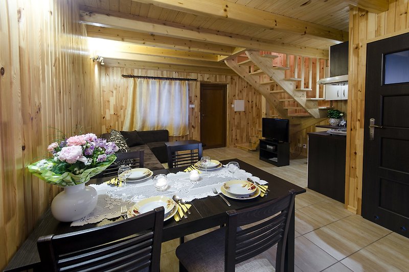 Küche mit Holzmöbeln, Tisch, Geschirr und Pflanzen.