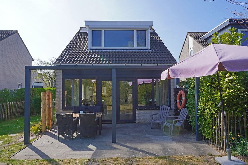 Einladende Terrasse mit Gartenmöbeln und blühenden Pflanzen.