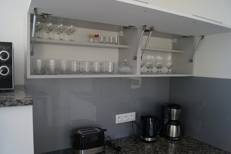 Moderne Küche mit Edelstahlgeräten, Kochfeld und Kühlschrank.