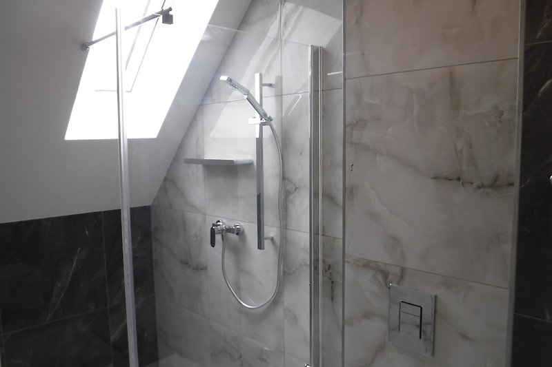 Modernes Badezimmer mit Dusche, Armatur und Glas.