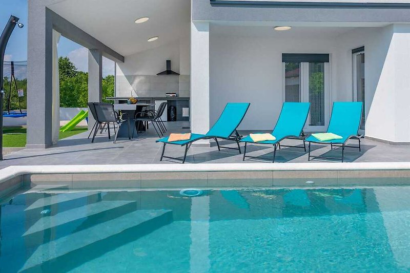 Tauchen Sie ein in den Pool und entspannen Sie auf den Sonnenliegen in dieser einladenden Villa.