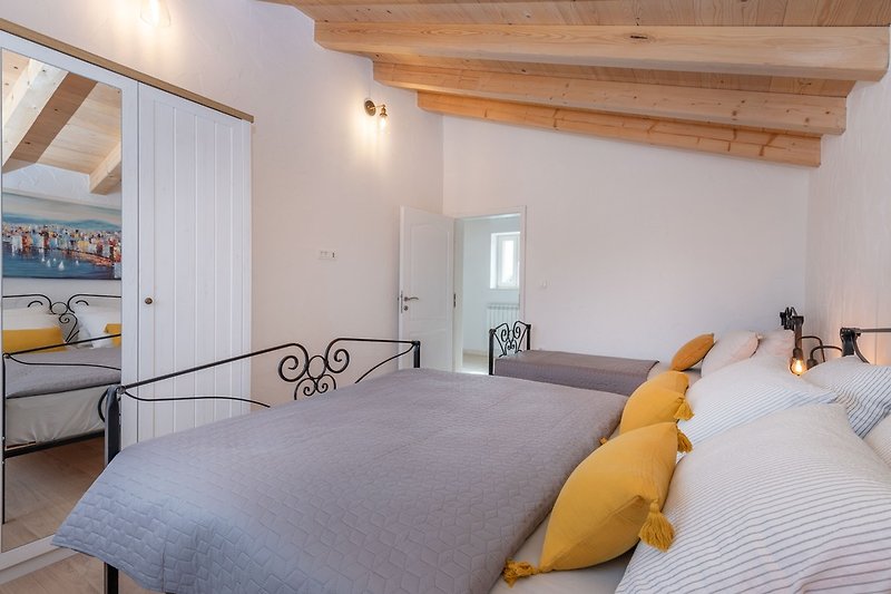 Genießen Sie einen ruhigen Schlaf in den gemütlichen Doppel- und Einzelbetten des ersten Schlafzimmers der Villa Leana.