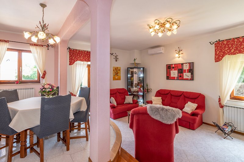 Das Wohnzimmer der Villa Ornela strahlt Raffinesse mit seinen lebhaften roten Sofas aus.
