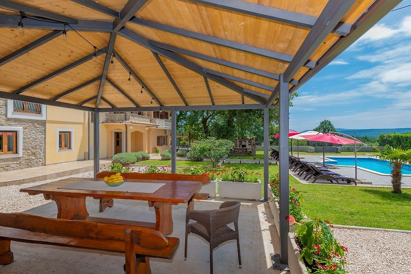 Genießen Sie köstliche Mahlzeiten auf der überdachten Terrasse der Villa Tupljak mit großem Esstisch.