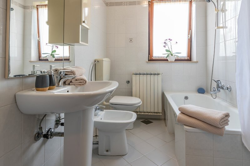 Gemütliches Badezimmer mit lila Akzenten, Spiegel und Badewanne.
