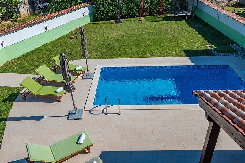 Schwimmbad mit Sonnenliegen und schattiger Terrasse