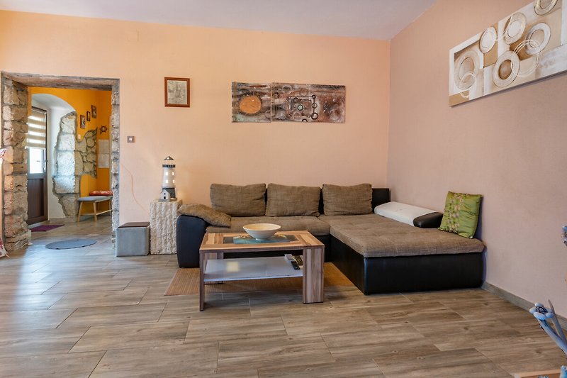 Wohnzimmer mit Holzboden, gemütlicher Couch und Kunst.
