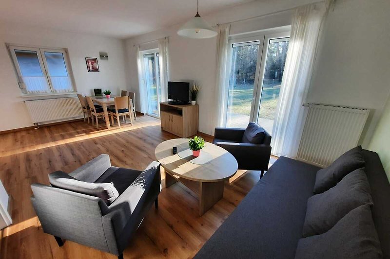 Gemütliches Wohnzimmer mit bequemer Couch, Holzmöbeln und großem Fenster.