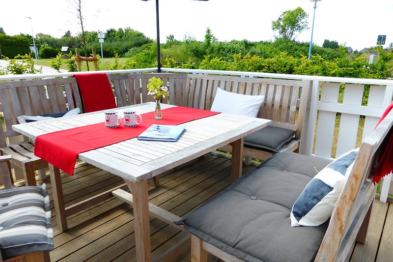 Gemütliche Terrasse mit Holzmöbeln und Blick auf den Garten.
