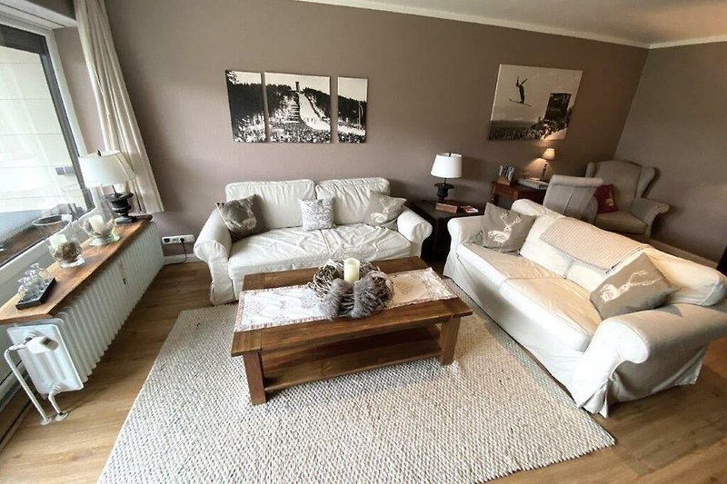 Gemütliches Wohnzimmer mit brauner Couch, Holzmöbeln und stilvoller Einrichtung.