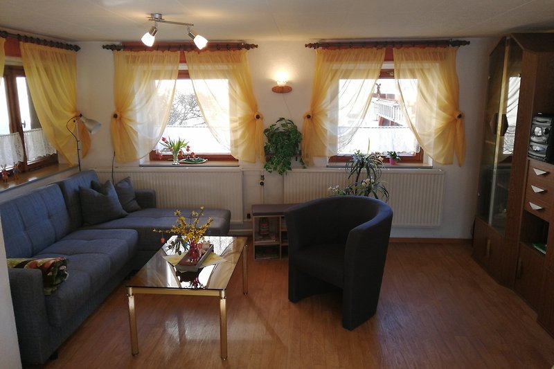 Gemütliches Wohnzimmer mit bequemer Couch, Tisch und Pflanze. Perfekt zum Entspannen.