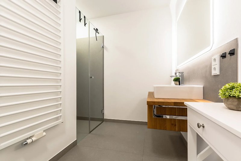 Modernes Badezimmer mit Holzmöbeln und stilvoller Beleuchtung.