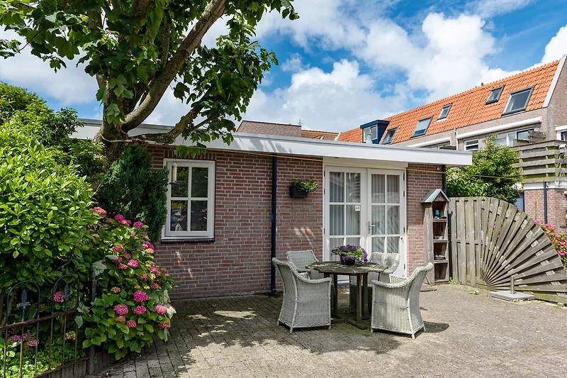 Charmantes Backsteinhaus mit Garten, Blumen und gepflegtem Rasen.