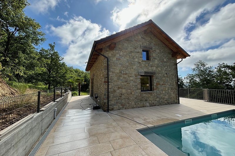 PICCO -  Aussenansicht Steinhaus, Terrasse mit beheizbarem Salzwasser-Pool, umgeben von Bäumen