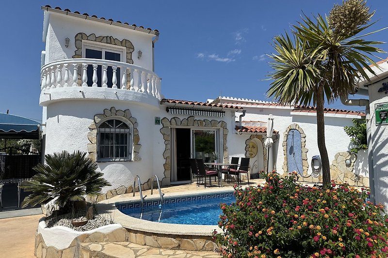 Villa mit Palmen, gepflegter Einfahrt und Balkon.