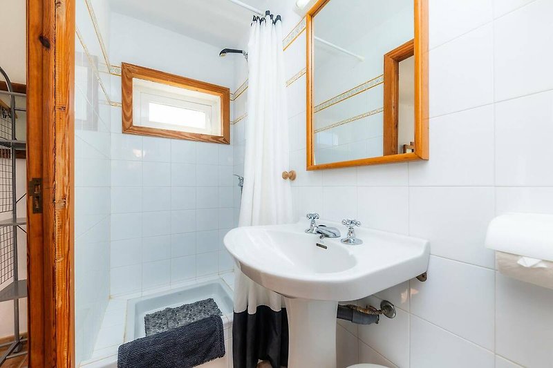 Schönes Badezimmer mit lila Fliesen, Holzboden und stilvoller Beleuchtung.