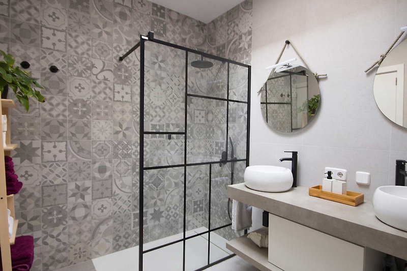 Badezimmer mit modernem Design, Spiegel, Waschbecken und Dusche.