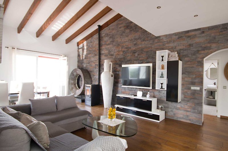 Wohnzimmer mit Fernseher, Holzmöbeln und gemütlicher Beleuchtung.