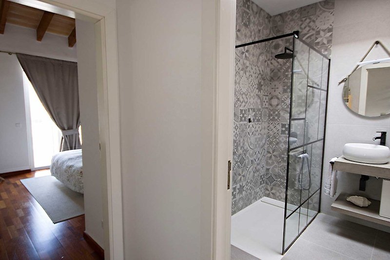 Badezimmer mit Holzmöbeln, Spiegel, Waschbecken und Fenster.