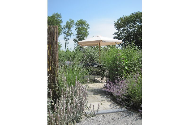 Die Terrasse ist mit Gartenmöbeln und einem Sonnenschirm ausgestattet.