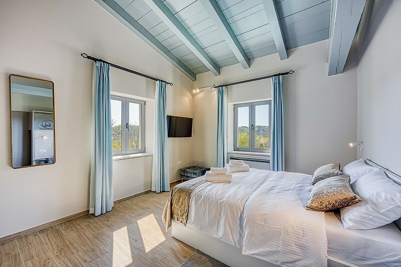 Schlafzimmer mit Holzbett, Fenster und Spiegel. Gemütliche Atmosphäre.