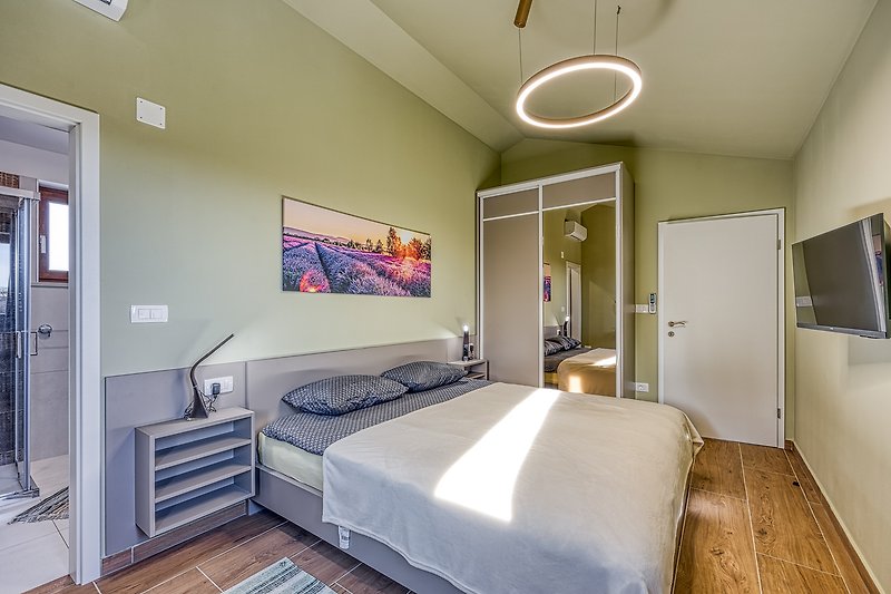 Schlafzimmer mit elegantem Bett, stilvoller Beleuchtung und Bilderrahmen.