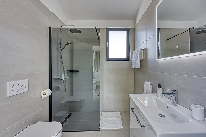 Modern bathroom with sleek fixtures and a glass shower panel.