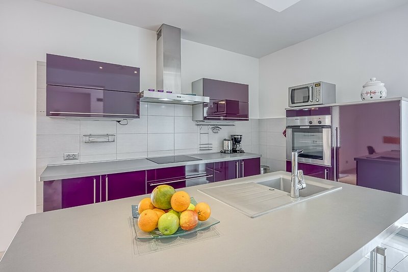 Moderne Küche mit violetten Schränken, orangefarbenen Arbeitsplatten und Holzboden.