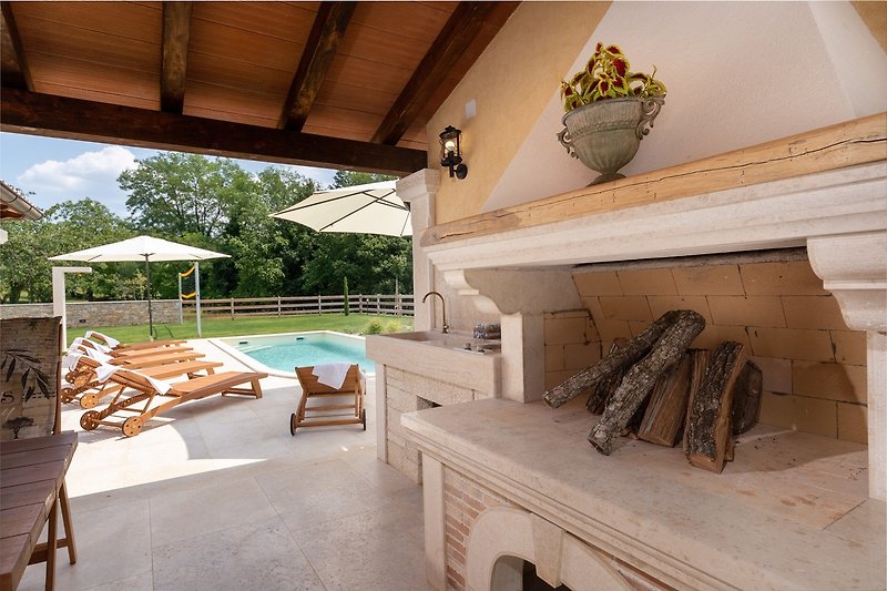 Schwimmbad mit moderner Architektur, Holzmöbeln und tropischer Landschaft.