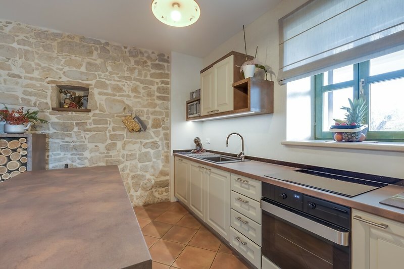Schöne Küche mit Holzschränken, Arbeitsplatte und Spülbecken.