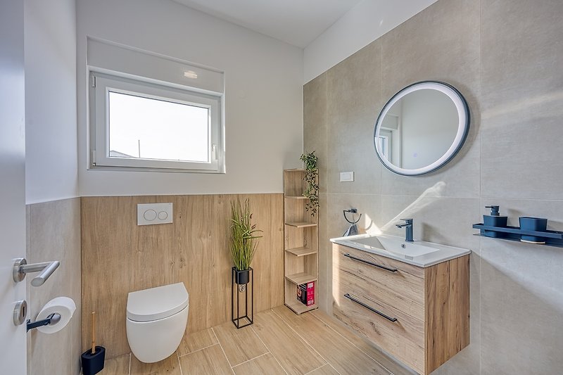 Badezimmer mit lila Akzenten, Spiegel, Waschbecken und Fenster.