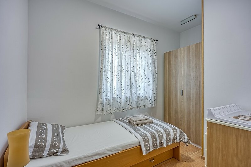 Gemütliches Schlafzimmer mit Holzmöbeln und Fensterdekoration.