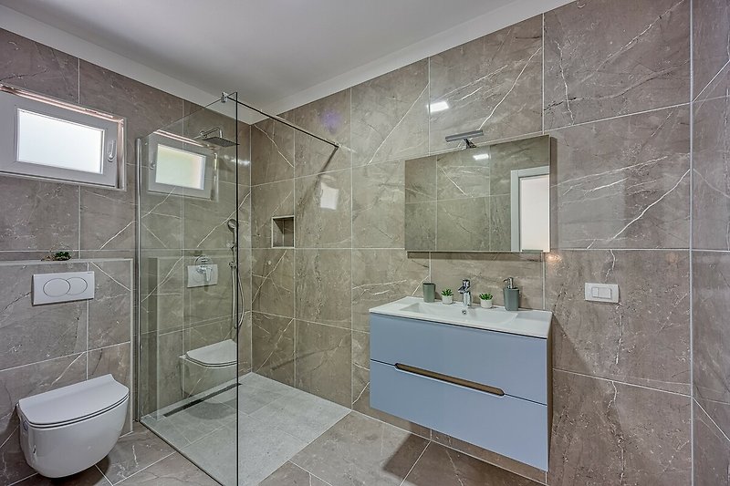 Stylish bathroom with modern fixtures and a sleek glass shower door.