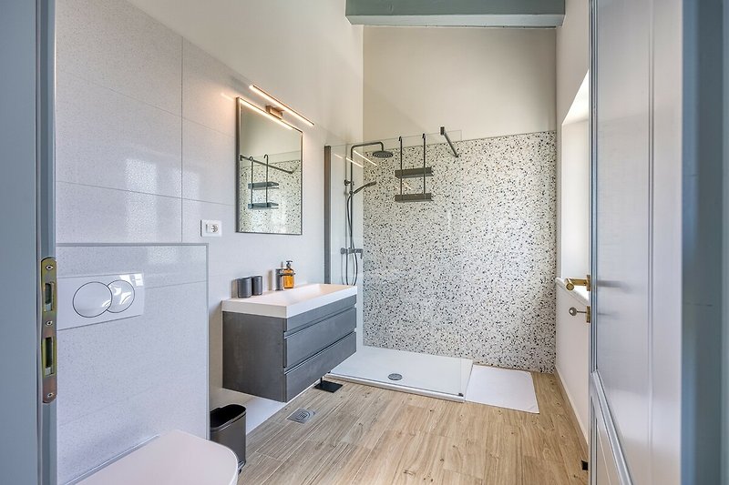 Modernes Badezimmer mit Holzdetails, Glasdusche und Spiegel.