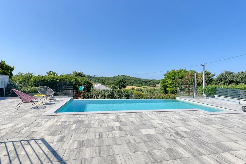 Schwimmbad, Pflanzen und Outdoor-Möbel in diesem Ferienhaus mit Blick auf Wasser und Himmel.