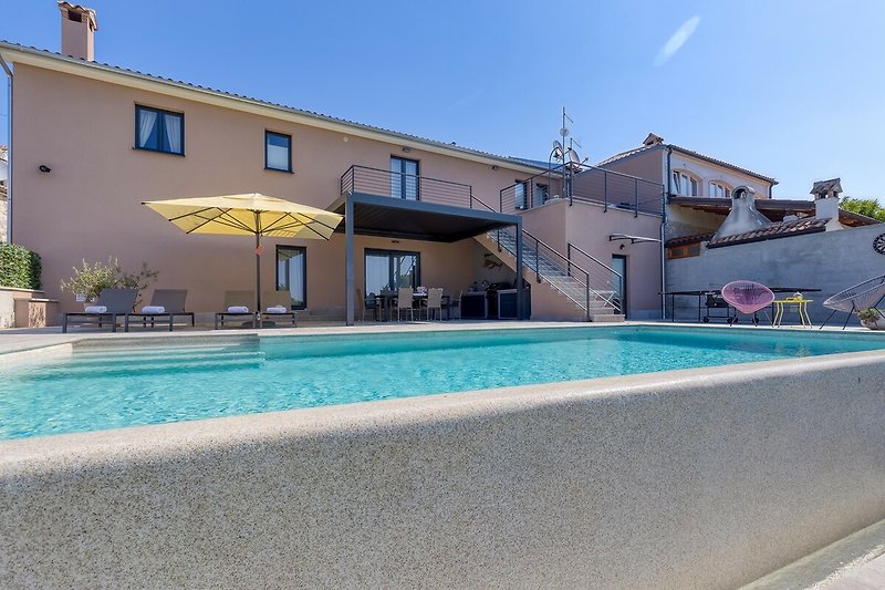 Schönes Haus mit Pool, blauem Wasser und stilvollem Design. Perfekt für einen erholsamen Urlaub.