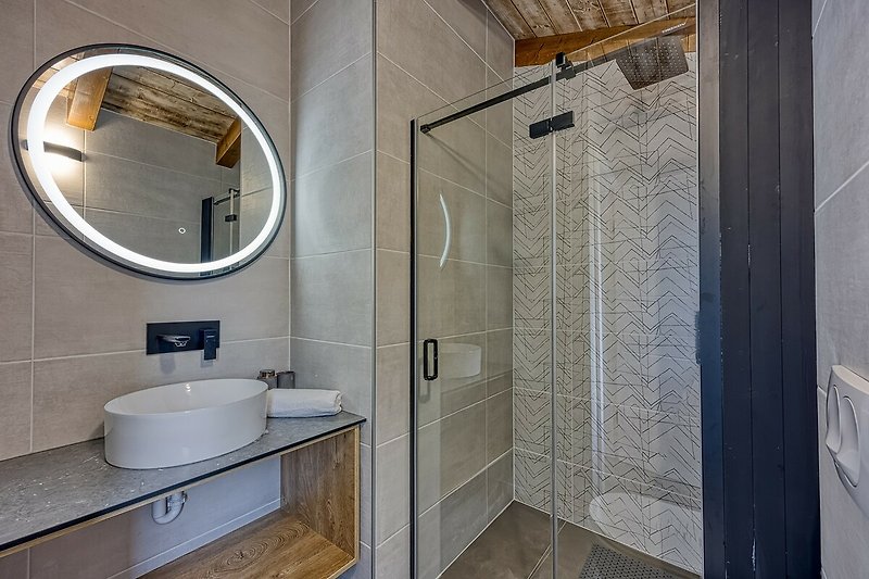 Stilvolles Badezimmer mit Spiegel, Wasserhahn und Waschbecken.