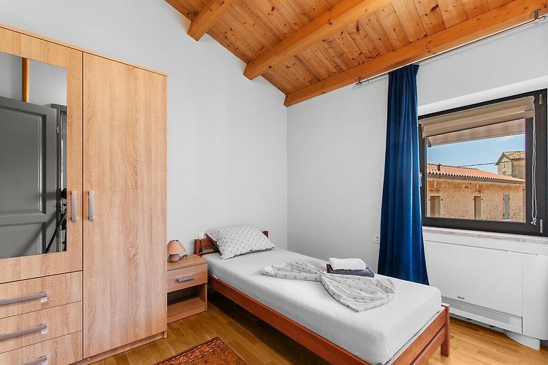 Gemütliches Schlafzimmer mit Holzmöbeln und stilvollem Fenster.