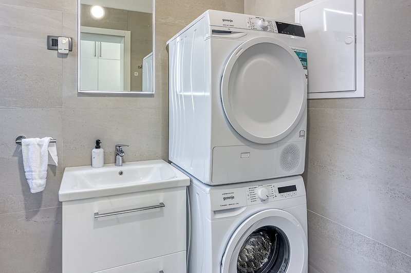 Spacious laundry room with modern appliances and a large mirror.