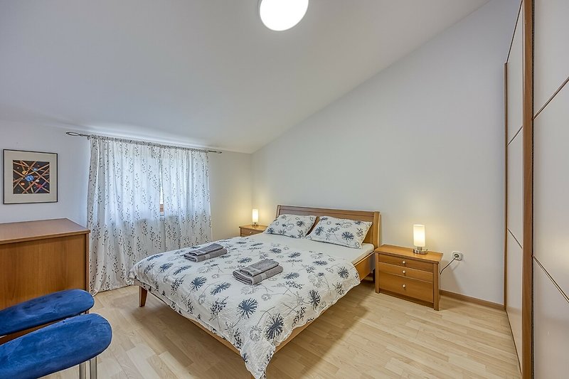 Gemütliches Schlafzimmer mit stilvollen Holzmöbeln und Fensterdekoration.