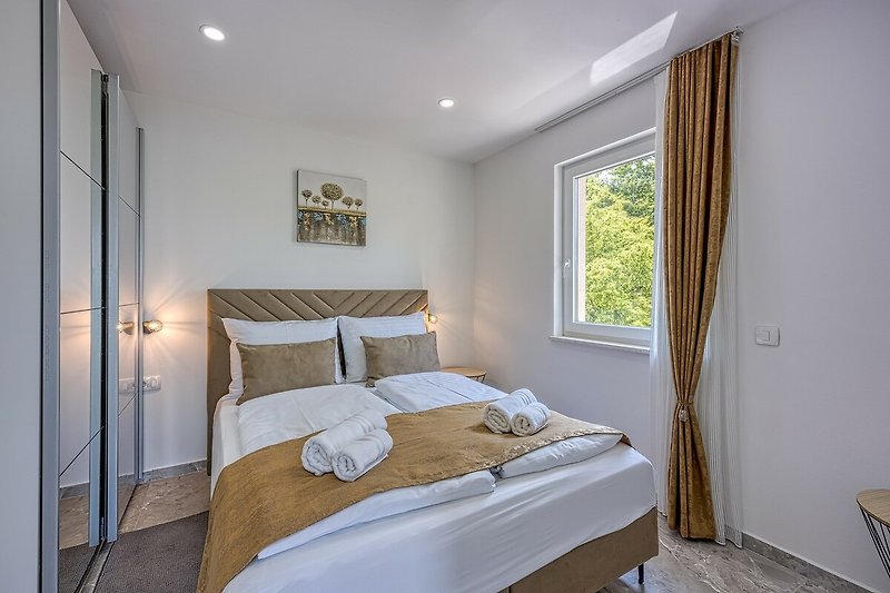 Comfortable bedroom with wood flooring, cozy bed, and stylish furniture.