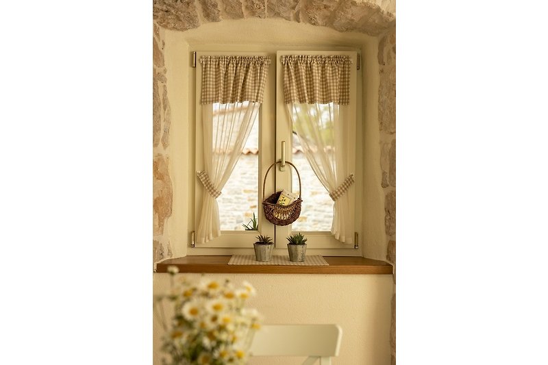 Elegante Fensterdekoration mit Blumen und Tischlampe. Gemütliche Atmosphäre.