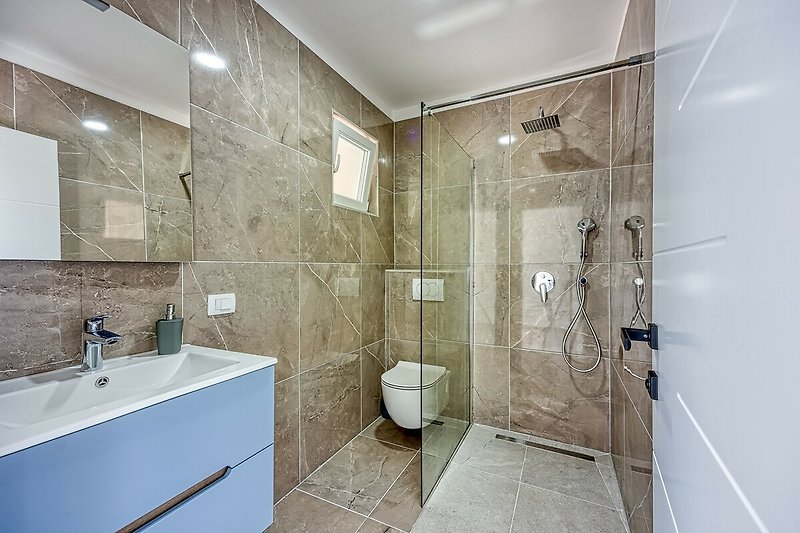 Stylish bathroom with a modern shower, sleek fixtures, and glass shower door.