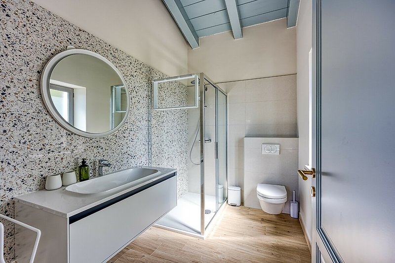 Modernes Badezimmer mit Holzdetails, Glasdusche und Spiegel.