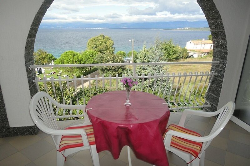Balkon mit Tisch, Stühlen und Pflanzen. Gemütliche Atmosphäre.